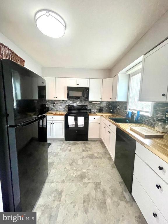 264 Fairfield Dr, Warrenton, VA 20186 - kitchen featuring black appliances, decorative backsplash, white cabinetry, and wood counters