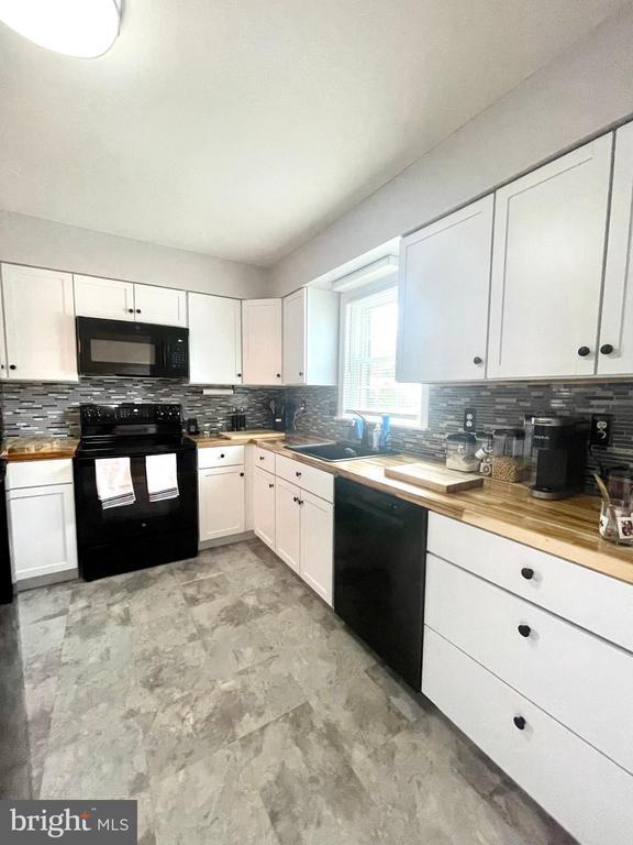 264 Fairfield Dr, Warrenton, VA 20186 - kitchen featuring black appliances, tasteful backsplash, and white cabinetry