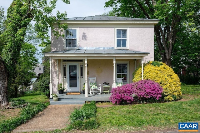 view of front of home with stucco siding, a standing seam roof, covered porch, and metal roof