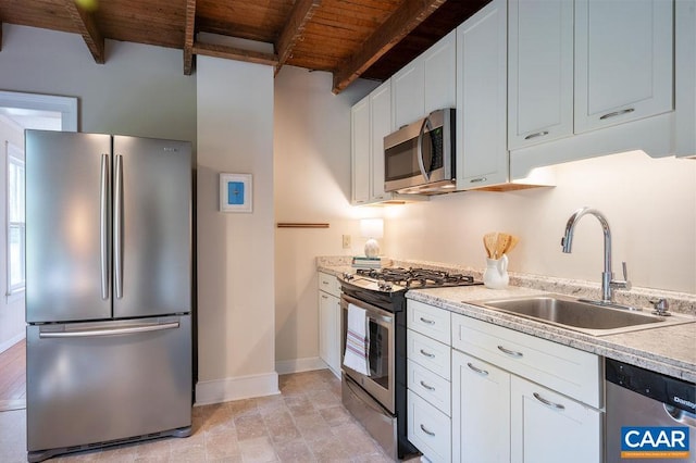 kitchen featuring appliances with stainless steel finishes, a sink, wooden ceiling, baseboards, and beam ceiling