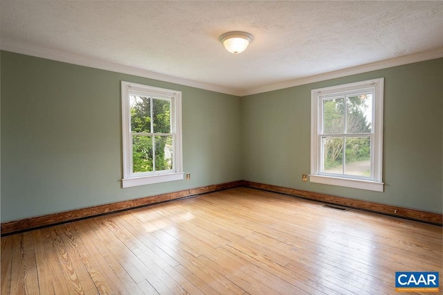 spare room featuring crown molding, a textured ceiling, wood-type flooring, and baseboards