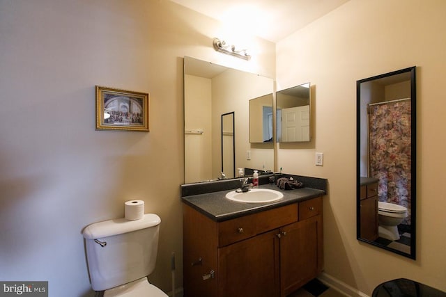 bathroom with toilet, vanity, and baseboards