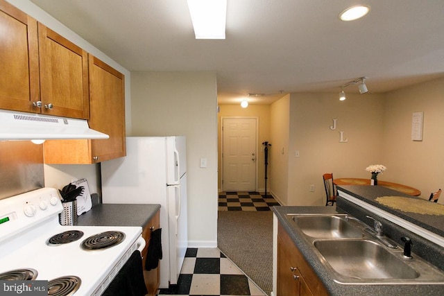 kitchen with white appliances, dark floors, under cabinet range hood, a sink, and brown cabinetry