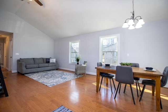 dining area featuring baseboards, wood finished floors, ceiling fan with notable chandelier, and vaulted ceiling