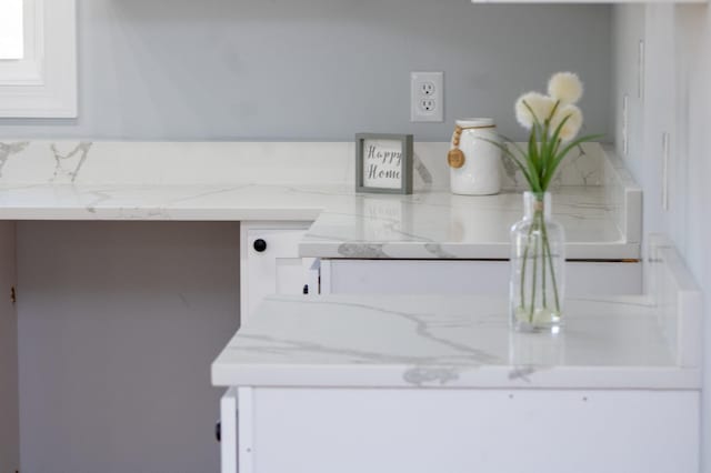 room details with white cabinets and light stone counters