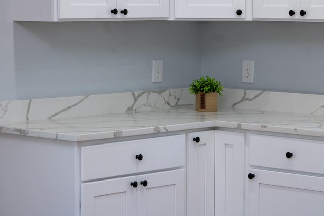kitchen with light stone countertops and white cabinetry