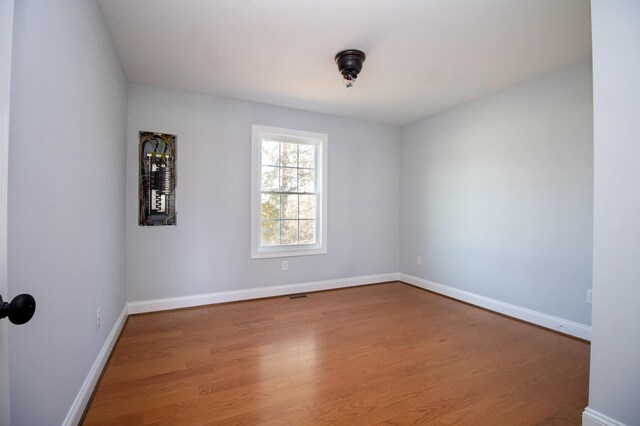 spare room with baseboards, visible vents, and wood finished floors