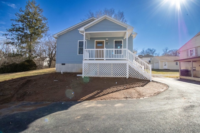 view of front of property featuring a porch, driveway, and crawl space
