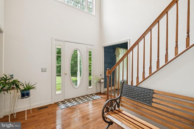 - entryway featuring stairway, wood finished floors, and a towering ceiling