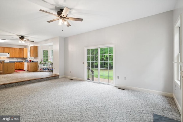  - unfurnished living room featuring a ceiling fan and light colored carpet