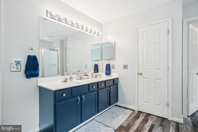  - full bathroom featuring double vanity, a shower stall, and wood finished floors
