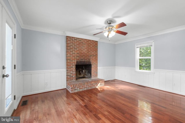 12218 Corter Ave, Fredericksburg, VA 22407 - unfurnished living room featuring hardwood / wood-style floors, ceiling fan, a wainscoted wall, a brick fireplace, and crown molding