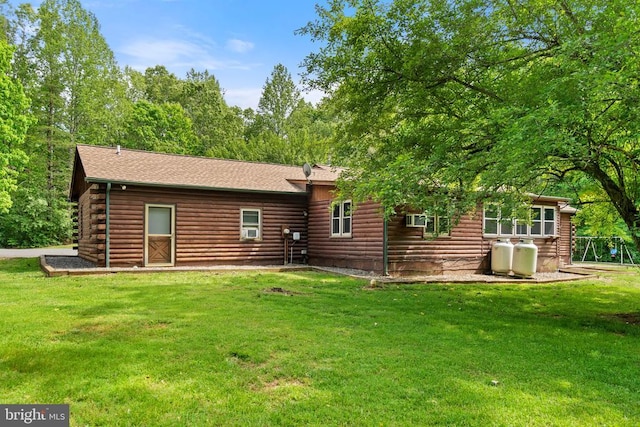 rear view of property featuring log exterior, a lawn, roof with shingles, and cooling unit