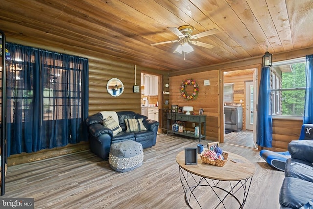 living area featuring washer / clothes dryer, wooden ceiling, wood finished floors, log walls, and ceiling fan