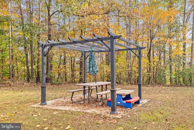 view of property's community featuring a pergola and a wooded view