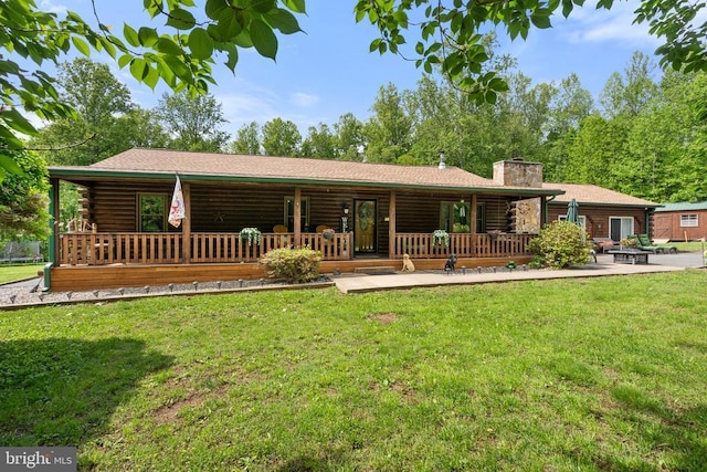 rear view of house featuring log exterior, a chimney, a lawn, and covered porch