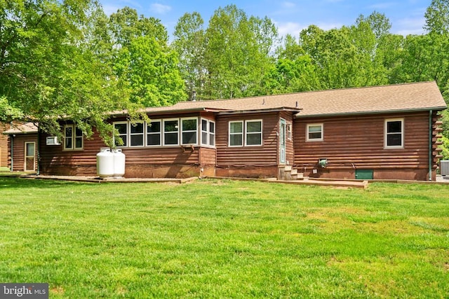 rear view of house with a lawn, log siding, entry steps, and a shingled roof