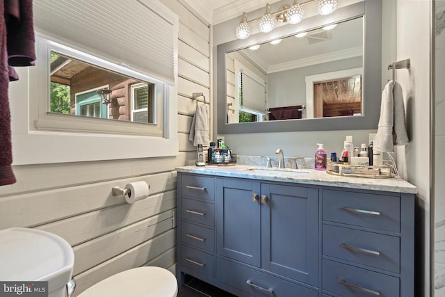 half bath with crown molding, toilet, vanity, and wood walls
