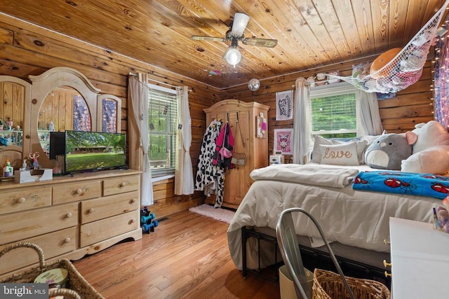 bedroom with wood ceiling, multiple windows, light wood finished floors, and wood walls