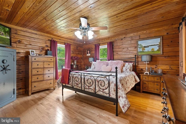 bedroom featuring light wood-style flooring, wooden ceiling, multiple windows, and wooden walls