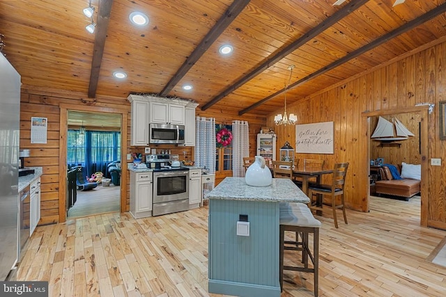 kitchen with appliances with stainless steel finishes, light wood-style flooring, wooden walls, wood ceiling, and a chandelier