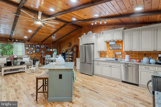 kitchen with stainless steel appliances, wood ceiling, a sink, light wood finished floors, and wood walls
