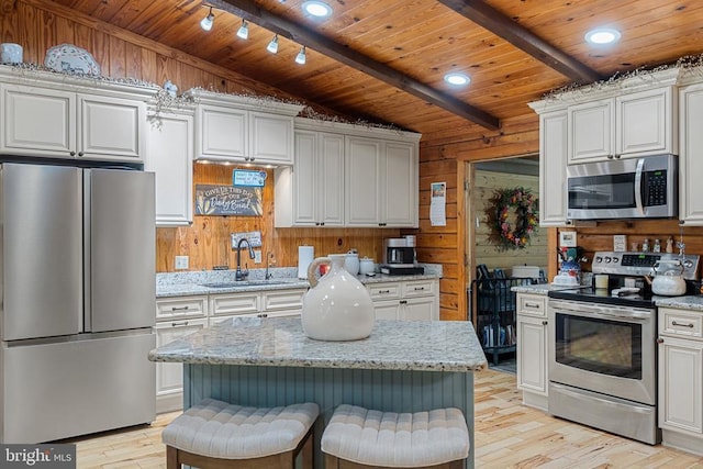 kitchen featuring appliances with stainless steel finishes, a sink, wood ceiling, light wood-style floors, and wood walls