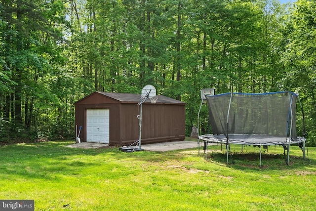 view of green lawn with a trampoline, an outdoor structure, and a garage