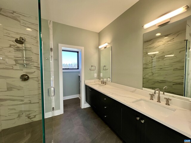 bathroom with a marble finish shower, baseboards, double vanity, and a sink