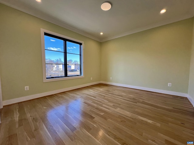 spare room with crown molding, wood finished floors, baseboards, and recessed lighting