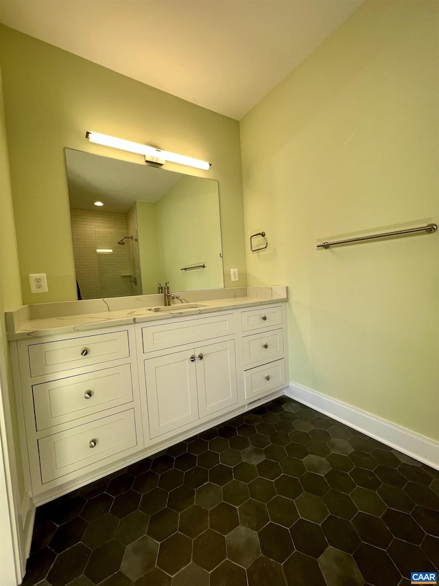 bathroom featuring vanity, baseboards, tiled shower, and tile patterned floors