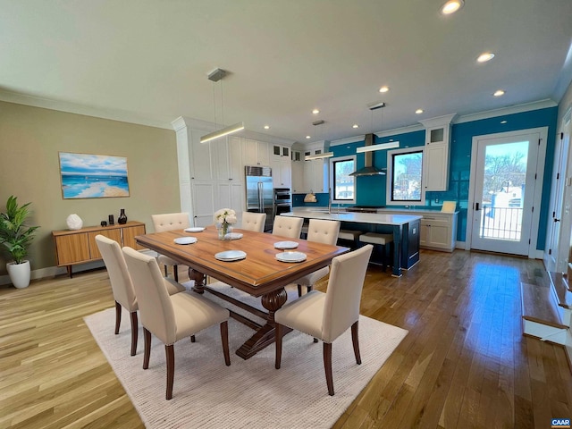 dining room featuring crown molding, wood finished floors, baseboards, and a healthy amount of sunlight