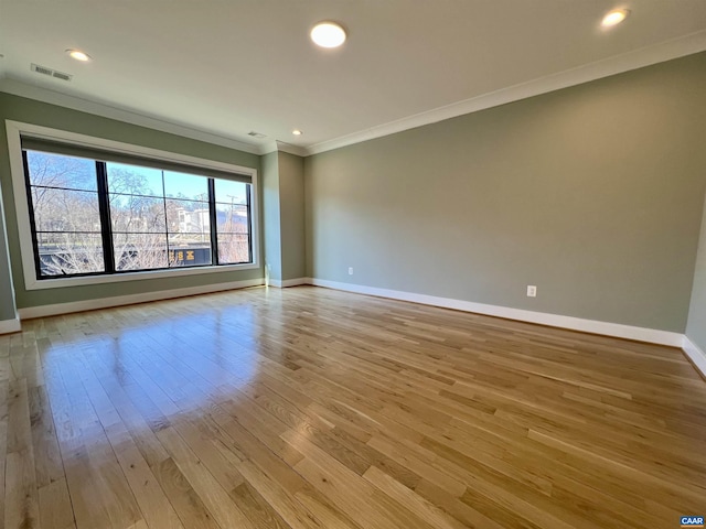 empty room featuring light wood-style flooring, crown molding, visible vents, baseboards, and recessed lighting