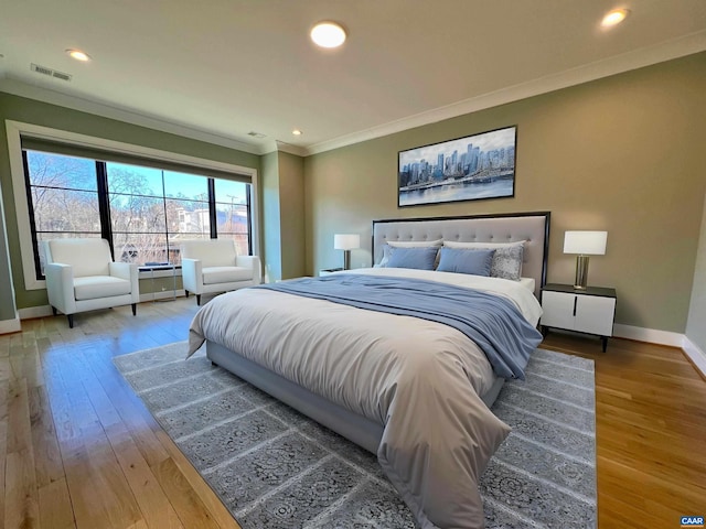 bedroom with crown molding, baseboards, hardwood / wood-style floors, and visible vents