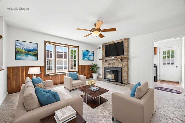 336 Hollingsworth Rd, Woodstock, VA 22664 - carpeted living room featuring healthy amount of natural light, a ceiling fan, a wainscoted wall, a fireplace, and wood walls
