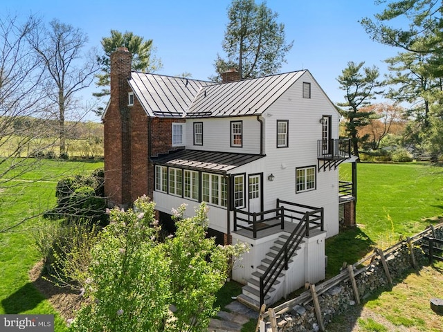 rear view of house with stairs, fence, metal roof, a chimney, and a standing seam roof