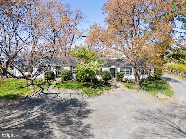 view of property hidden behind natural elements featuring fence and a front lawn