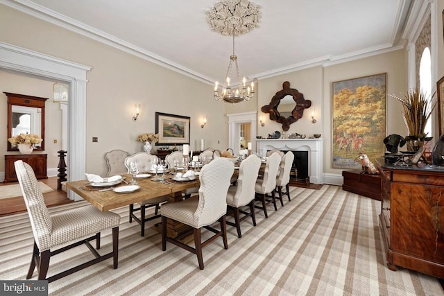 dining room featuring a fireplace, light carpet, ornamental molding, and a notable chandelier