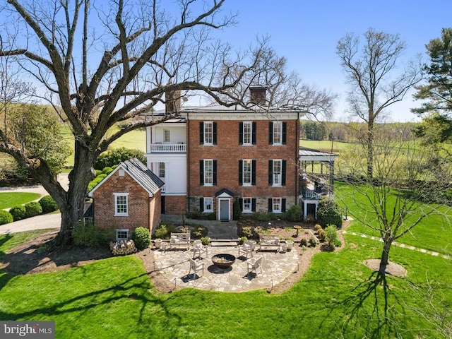exterior space featuring a patio area, a fire pit, brick siding, a balcony, and a front yard