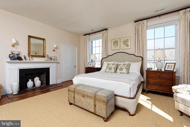 bedroom with a fireplace with flush hearth and visible vents