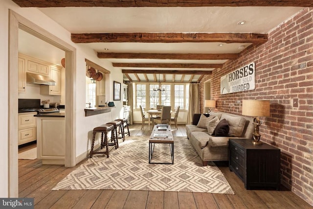 living room with light wood-style floors, baseboards, beamed ceiling, and brick wall