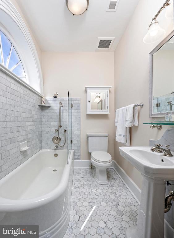 bathroom featuring toilet, shower / washtub combination, baseboards, and visible vents