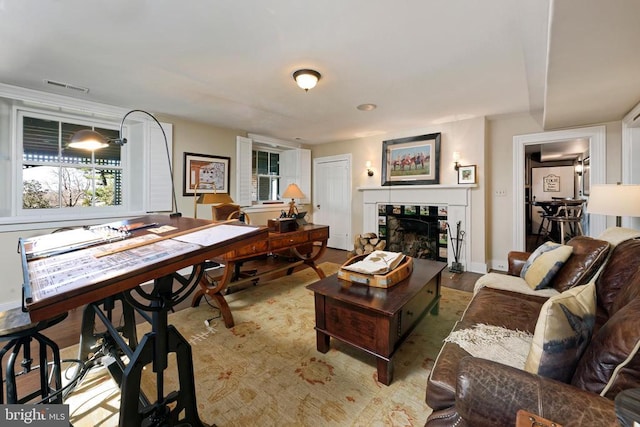living area featuring baseboards, a fireplace, visible vents, and wood finished floors