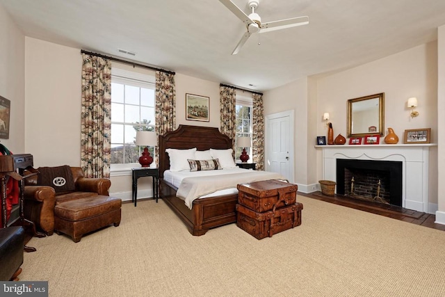 bedroom featuring ceiling fan, visible vents, baseboards, and a fireplace with flush hearth
