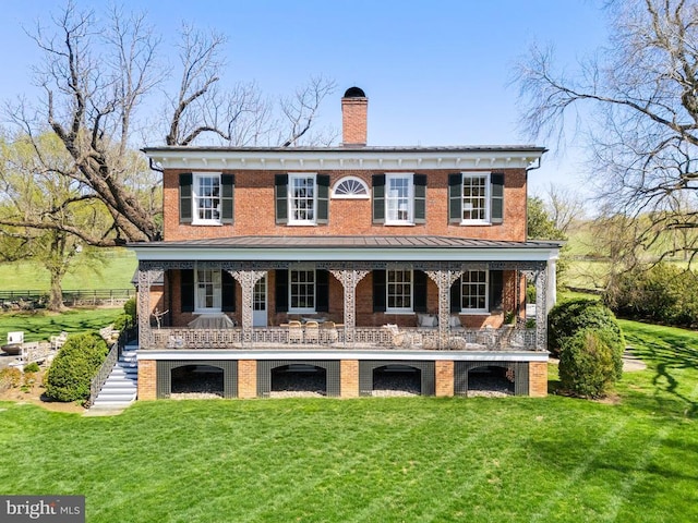 rear view of property featuring a chimney, a yard, and brick siding