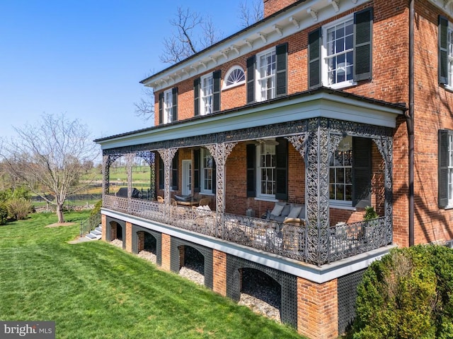 exterior space with a chimney, brick siding, and a front lawn