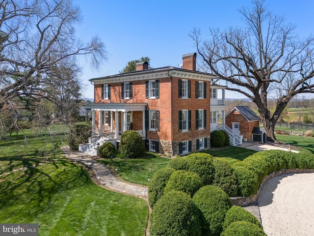 view of front of property with covered porch, fence, a chimney, a front yard, and brick siding
