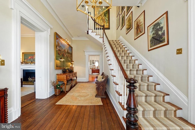 foyer entrance featuring baseboards, ornamental molding, stairs, hardwood / wood-style flooring, and a fireplace