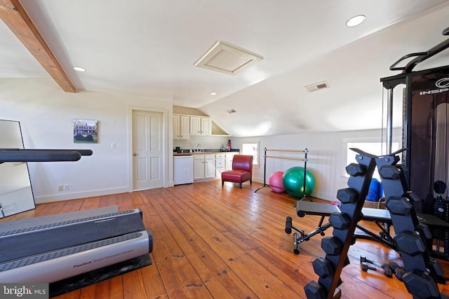 workout area featuring attic access, visible vents, baseboards, light wood-style floors, and lofted ceiling