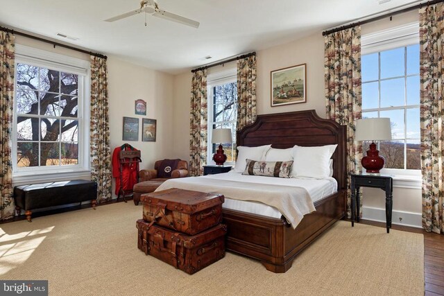 bedroom with ceiling fan, visible vents, and wood finished floors